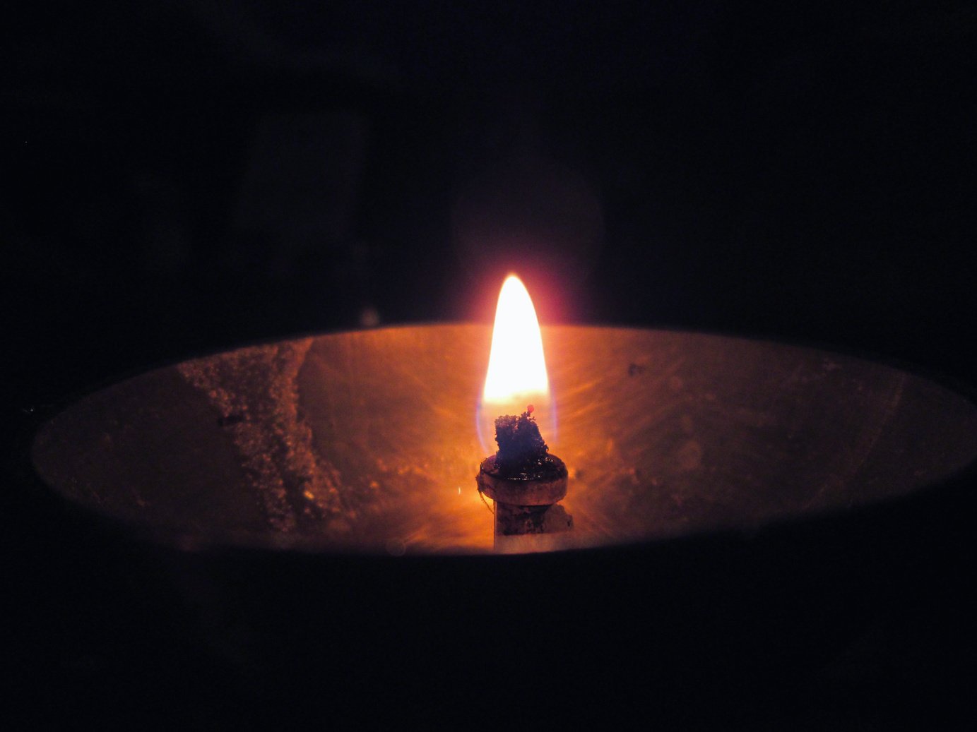 A close up of a lit diya in a dark room.